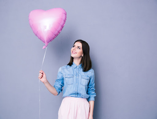 woman holding a pink heart shaped balloon
