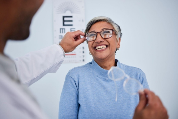 smiling woman getting fitted with glasses