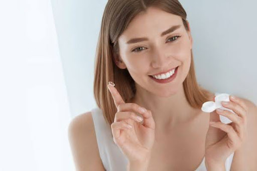 smiling woman holding a contact lense